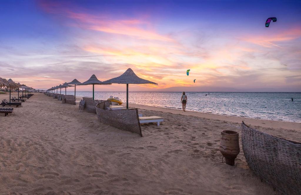 a beach with umbrellas and a person flying a kite at Fade Hotel by La Hacienda Ras Sudr in Ras Matarma