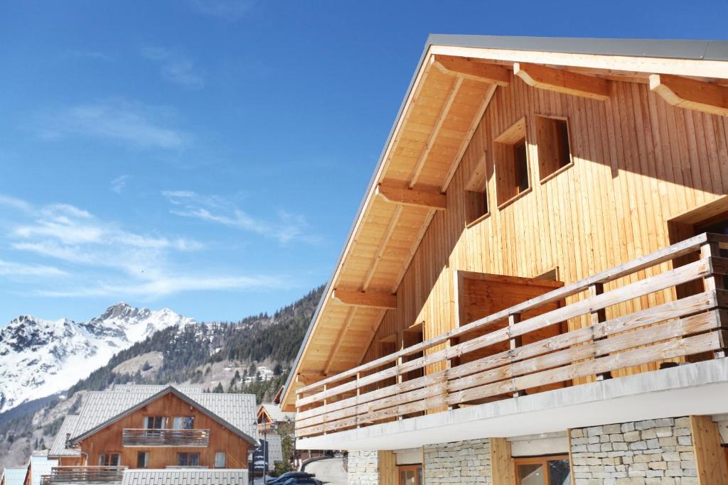 ein Holzgebäude mit Bergen im Hintergrund in der Unterkunft Résidence Goélia Le Crystal in Vaujany