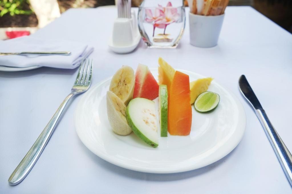 un piatto bianco con fette di frutta su un tavolo di Suriya Homestay Mirissa a Mirissa