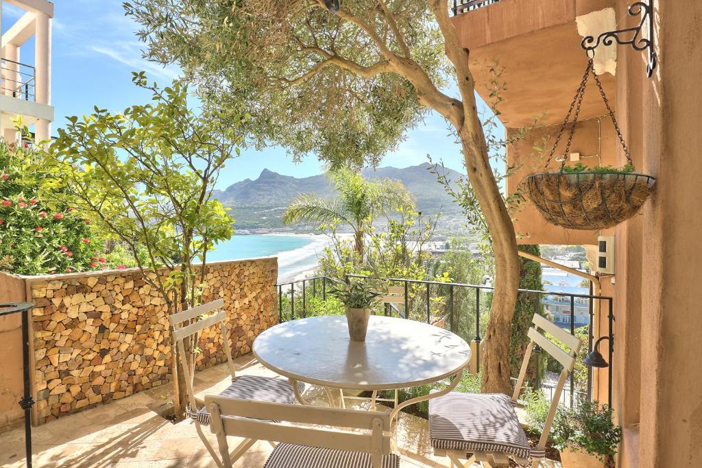 a table and chairs on a balcony with a view of the ocean at Dar El Hout in Hout Bay