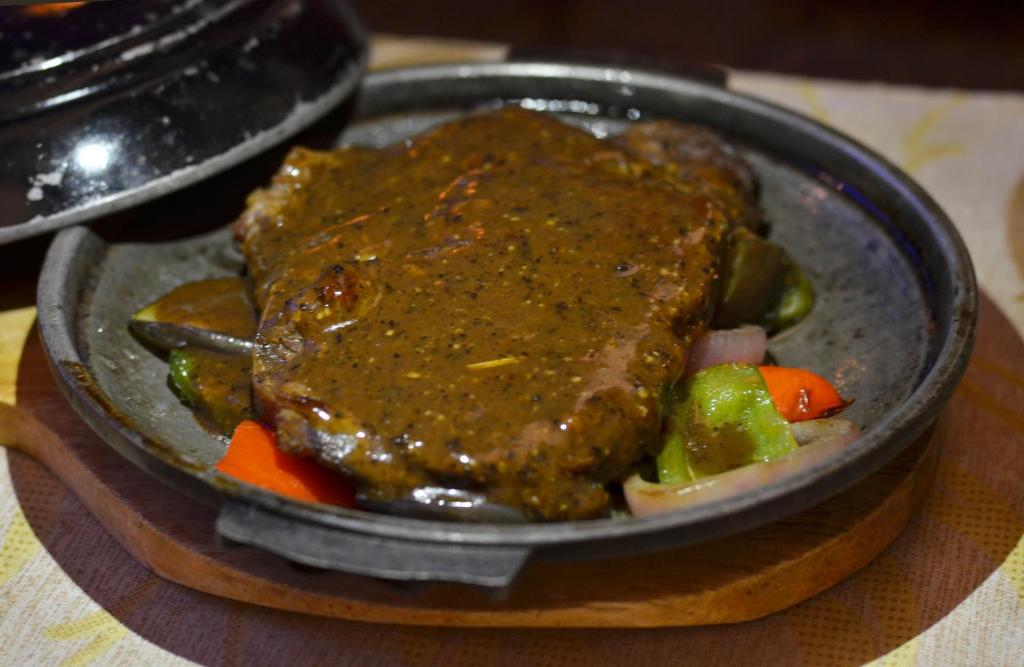 a plate of food with meat and vegetables on a table at Eagle Point Beach and Dive Resort in Mabini