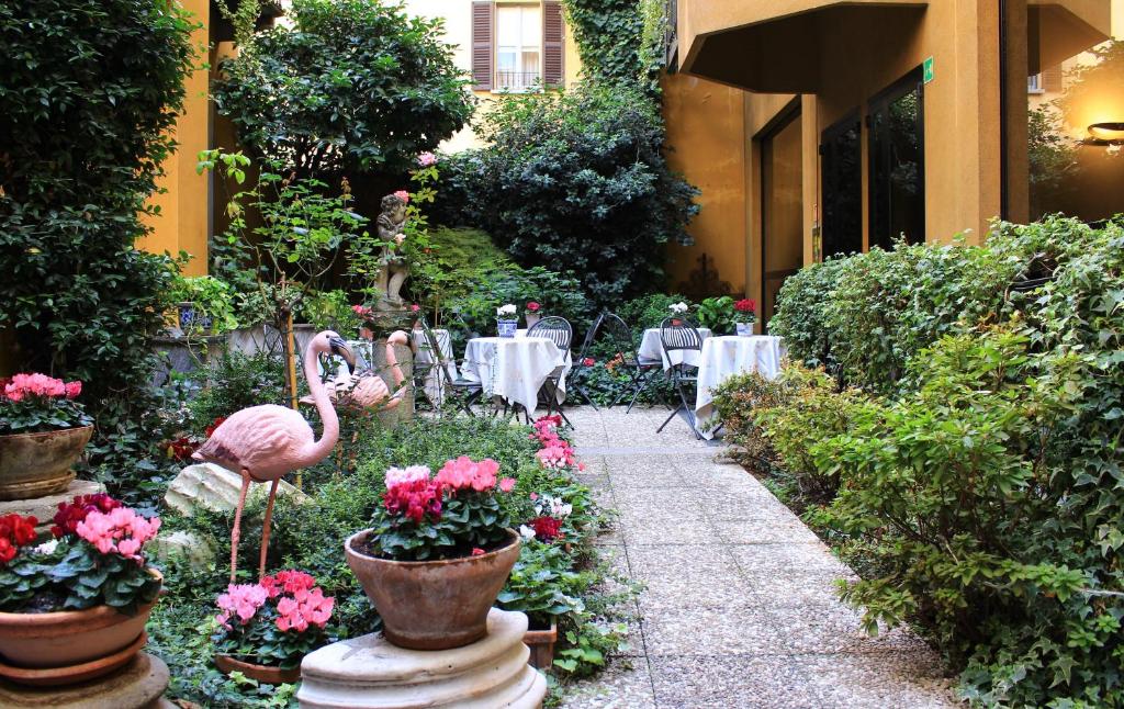 un jardín con un flamenco, mesas y flores en Hotel Sanpi Milano en Milán