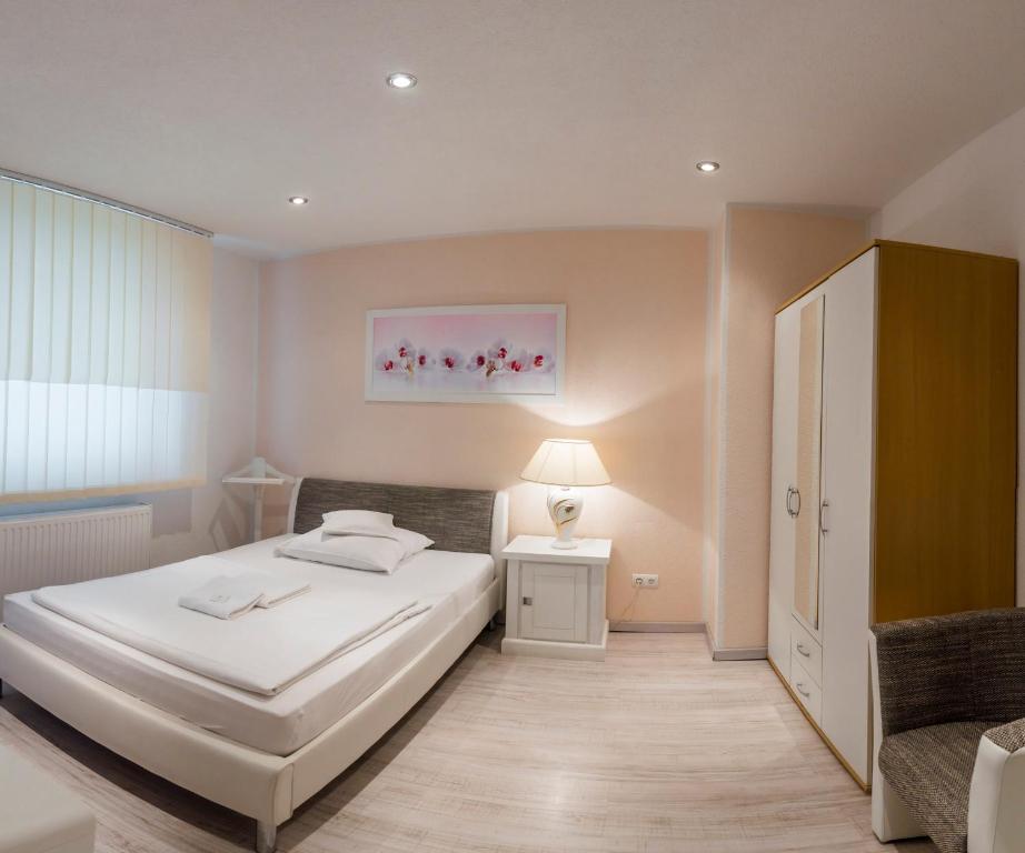 um quarto com uma cama branca e uma cadeira em Pension Donau em Hanôver