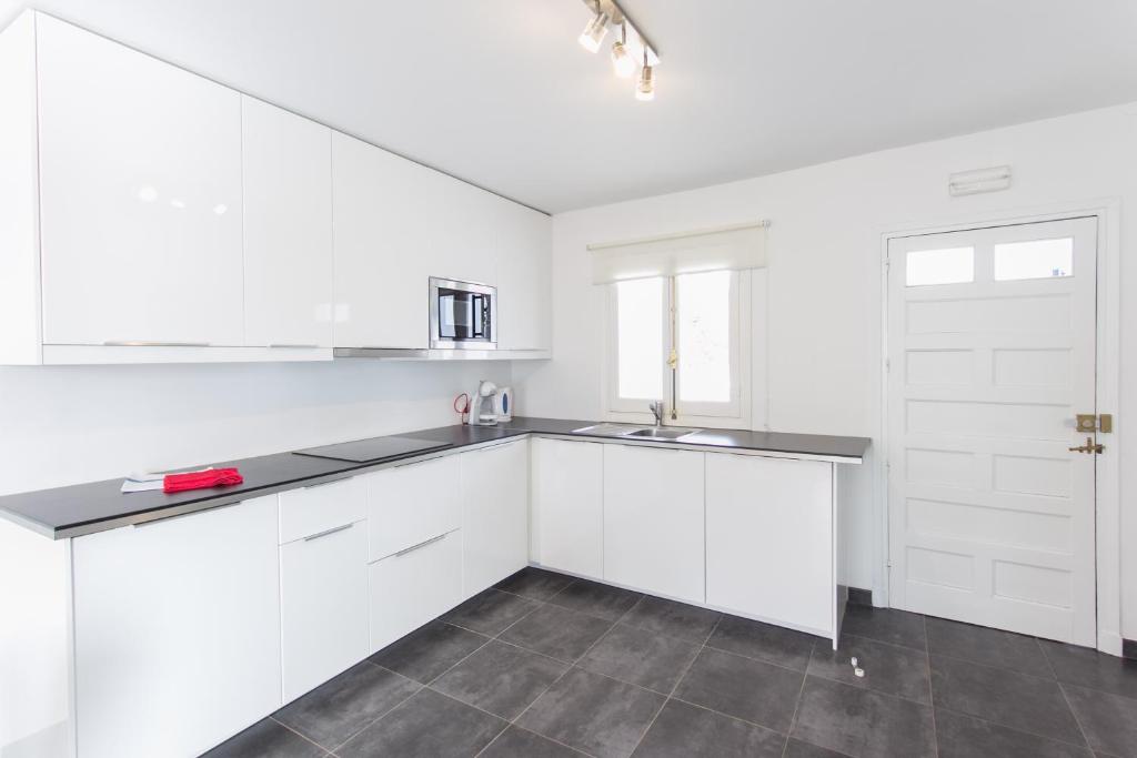 a white kitchen with white cabinets and a sink at Apartamentos Gama in Cala Galdana