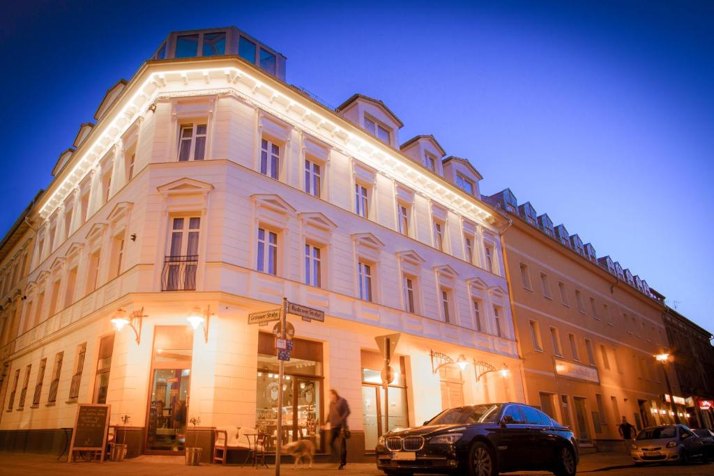 un edificio blanco con un coche aparcado delante de él en Hotel Bett und Buch, en Berlín
