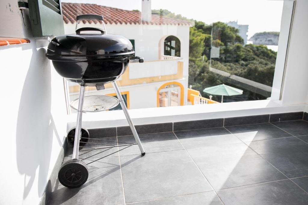 a grill on a stand in a kitchen with a window at Apartamentos Gama in Cala Galdana