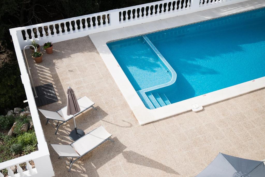 uma vista superior de uma piscina com duas cadeiras de jardim em Apartamento Gama em Cala Galdana