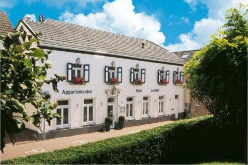 Un grand bâtiment blanc avec des fenêtres donne sur une rue. dans l'établissement Appartementen Hotel Geuldal, à Epen