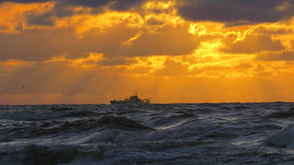 Ein Schiff im Ozean mit Sonnenuntergang in der Unterkunft Holiday Home Emmastraat in Katwijk