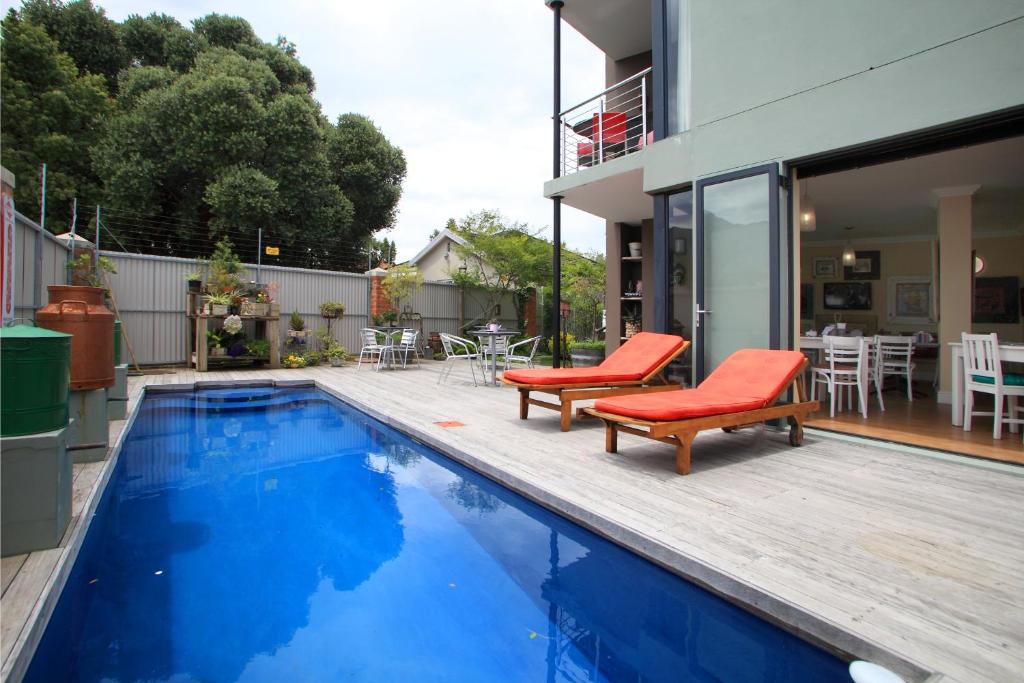 a swimming pool with two red chairs next to a house at 17onWellington Suites in George