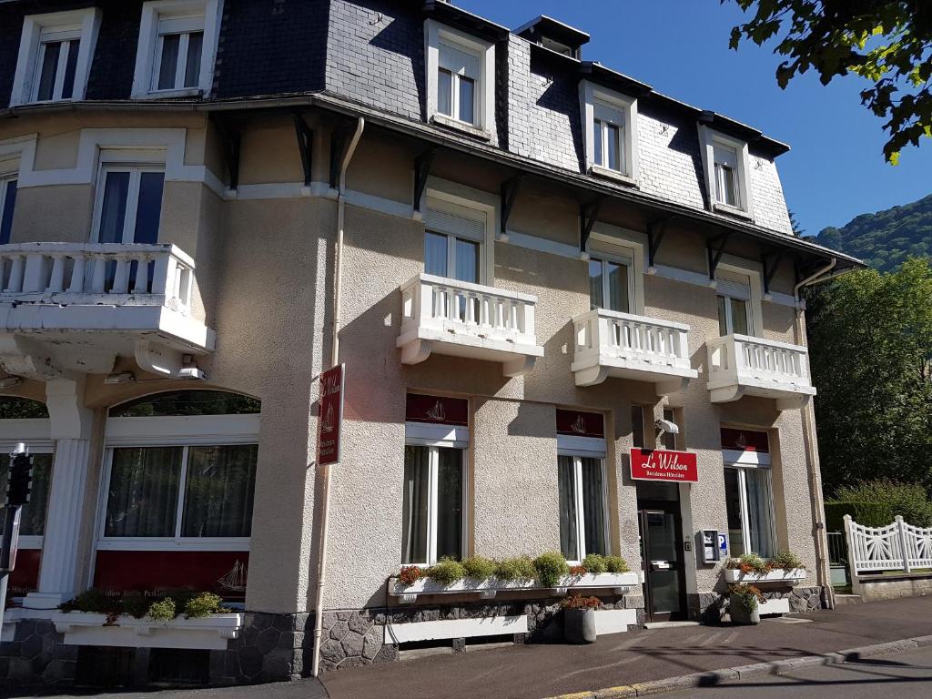 un gran edificio con balcones blancos en una calle en Résidence Wilson, en Le Mont-Dore