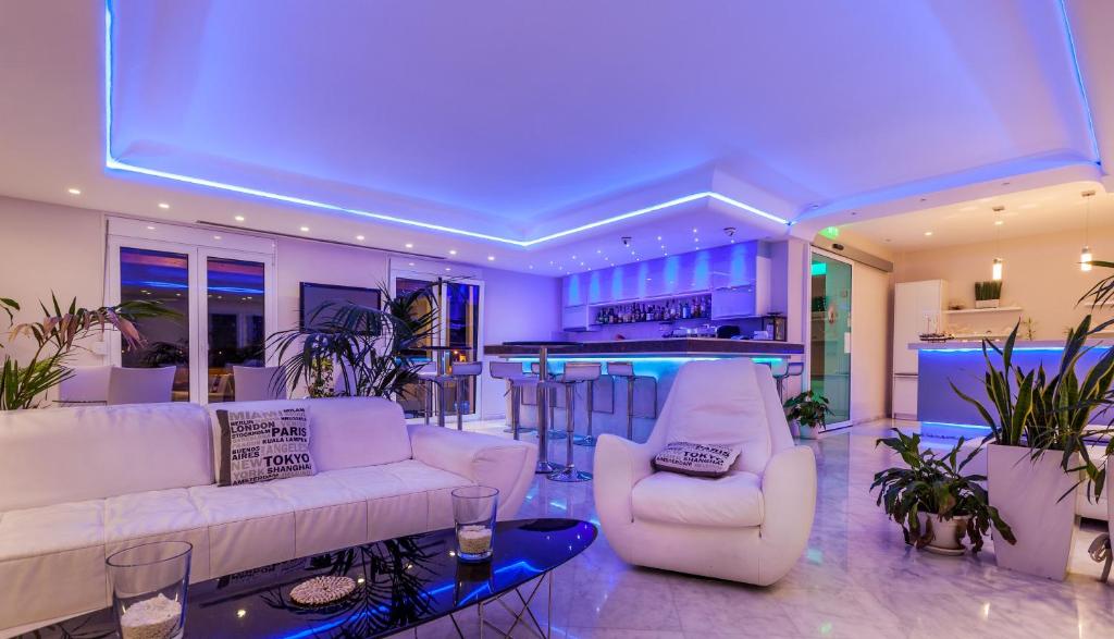 uma sala de estar com dois sofás brancos e um bar em Pearl Bay Hotel Apartments em Vrontádos