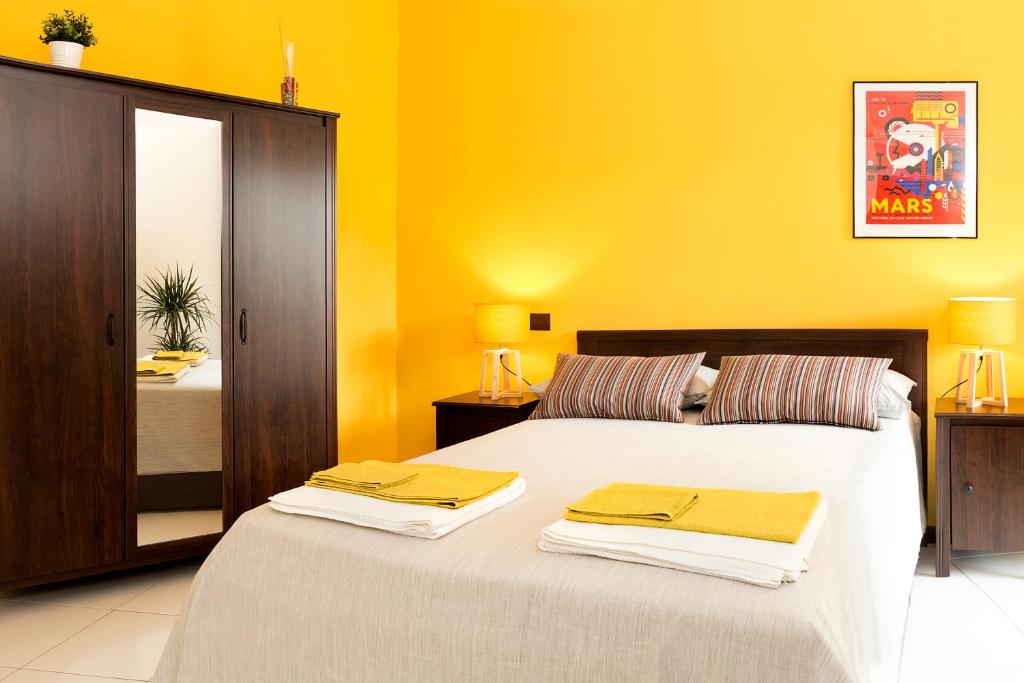 a bedroom with two beds and a yellow wall at B&B Cozy Cove in Torre del Greco
