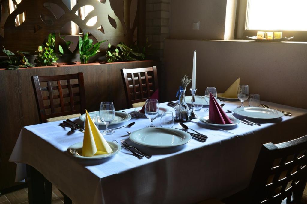 una mesa con un mantel blanco con platos y copas de vino en Hotel Elizabeth, en Baja