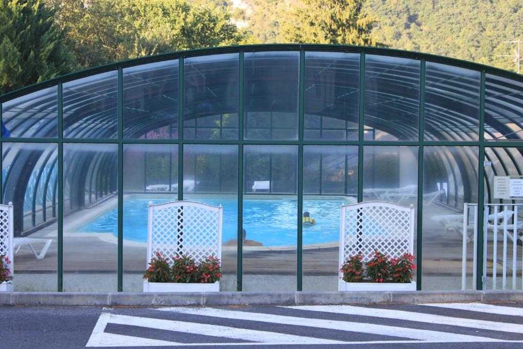 a glass building with a swimming pool in it at Résidence Les Marquises in Aspin-en-Lavedan