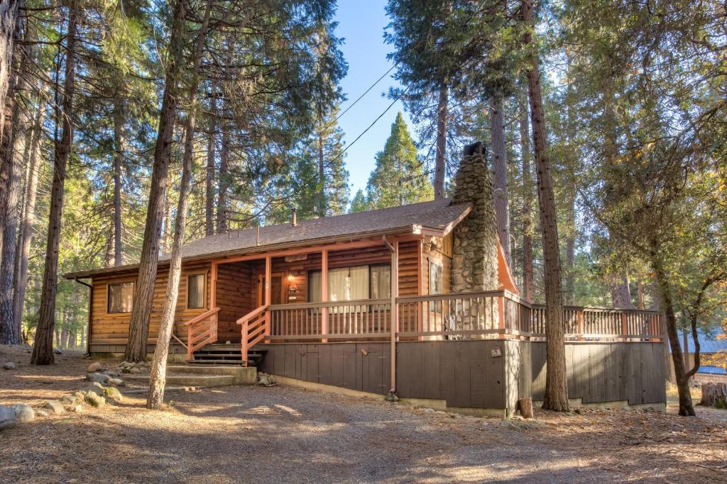 a cabin in the woods with a large deck at 55 Deer Creek in Wawona