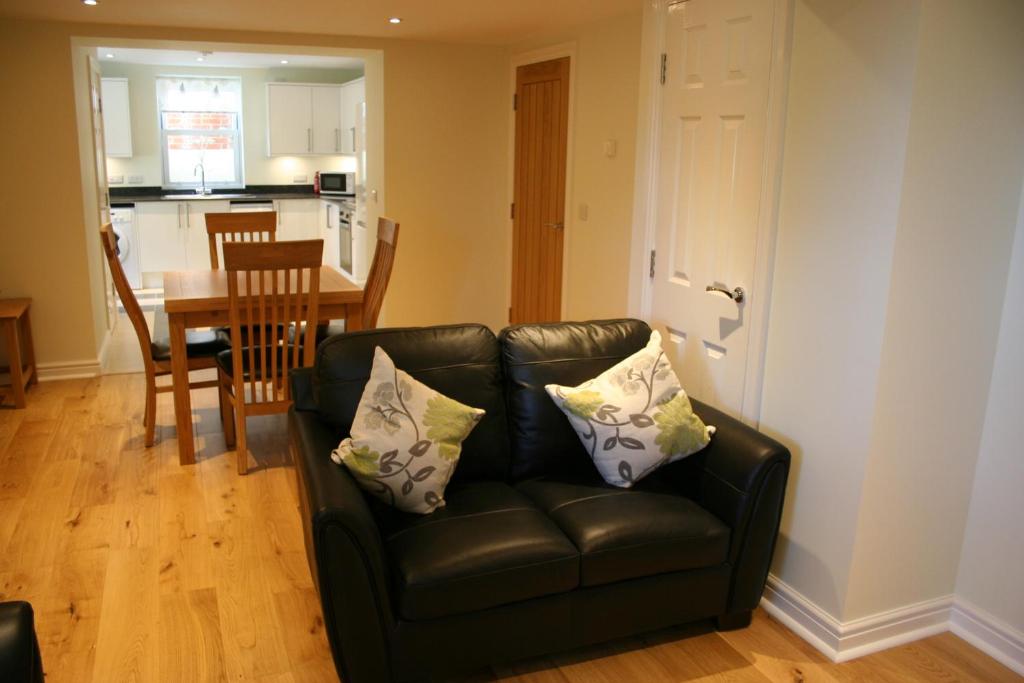 a black leather couch in a living room with a table at Highlands Apartment 5 in Shanklin