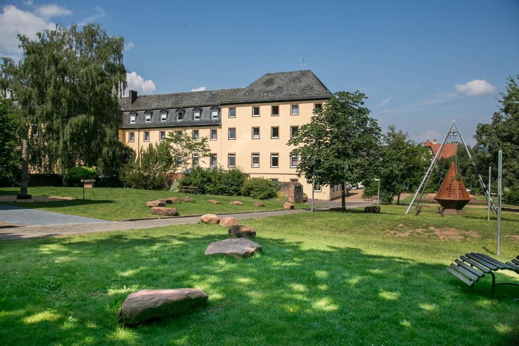 ein Gebäude mit Felsen im Gras davor in der Unterkunft Jugendhaus St. Kilian in Miltenberg