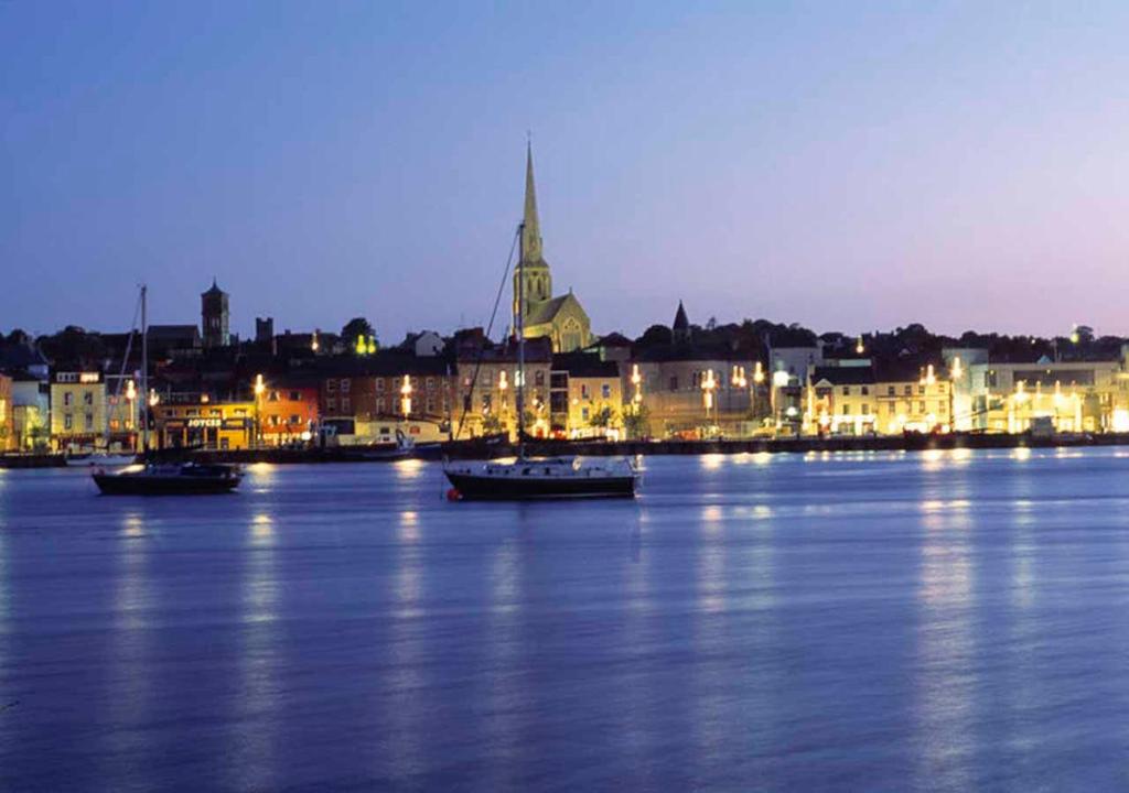 a city with boats in the water at night at Wexford Town Opera Mews - 1 Bed Apartment in Wexford