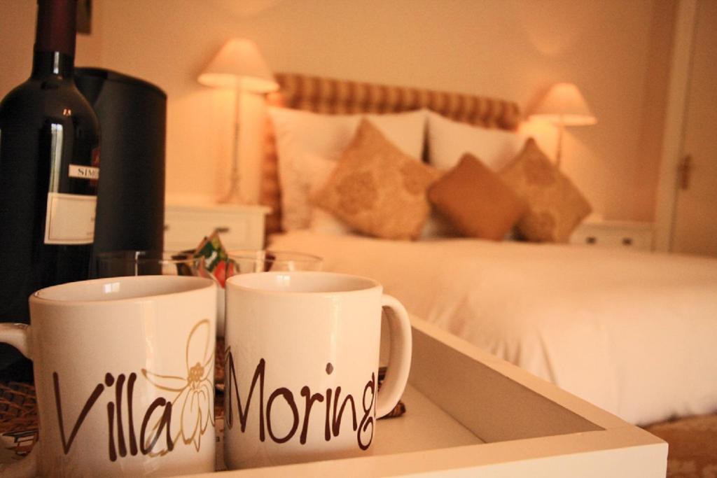 two coffee mugs sitting on a tray next to a bed at Villa Moringa Guesthouse in Windhoek
