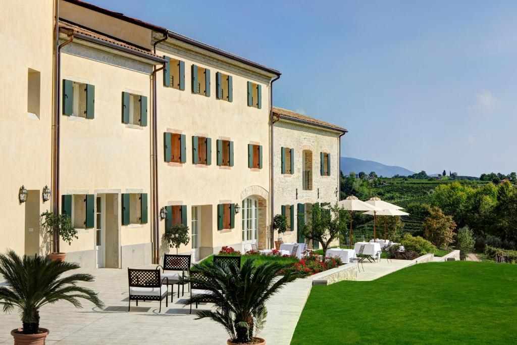 a large building with a patio and a lawn at Colonìa Resort in Vittorio Veneto