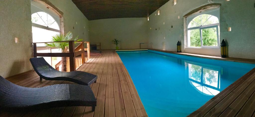 a swimming pool in a room with two chairs and a table at Moulin De Jouenery Et Spa in Brassac