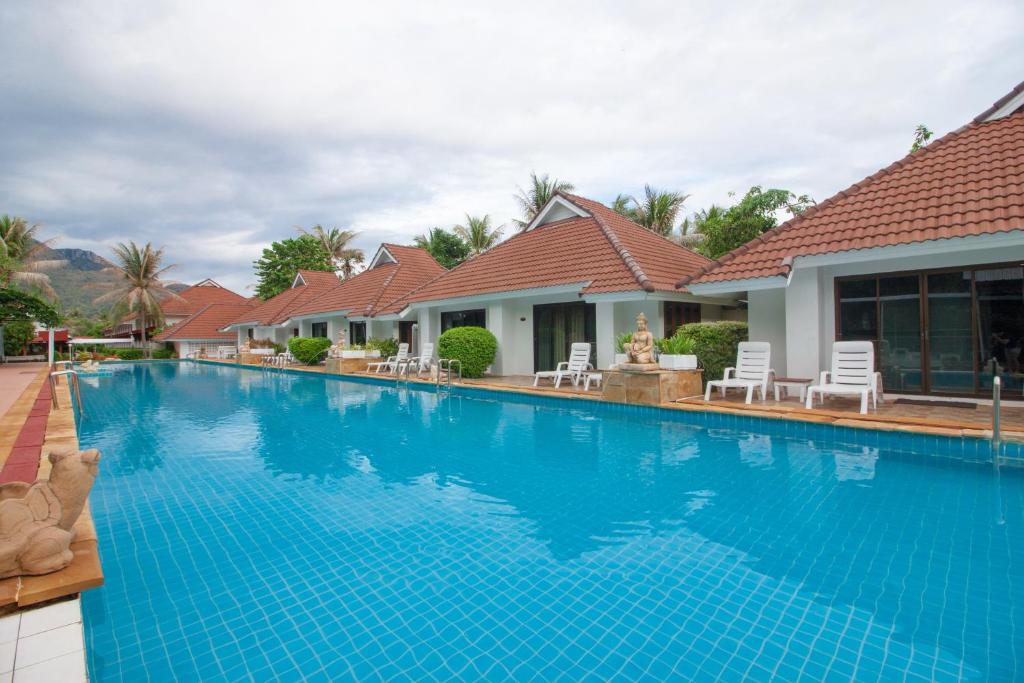 une grande piscine bleue en face d'une maison dans l'établissement The Privacy Beach Resort & Spa, à Sam Roi Yot