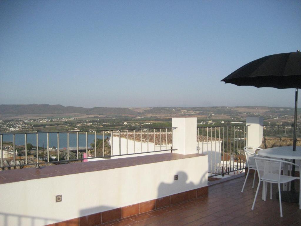 einen Balkon mit einem Tisch und einem Sonnenschirm in der Unterkunft CASA SAN ANTÓN in Arcos de la Frontera