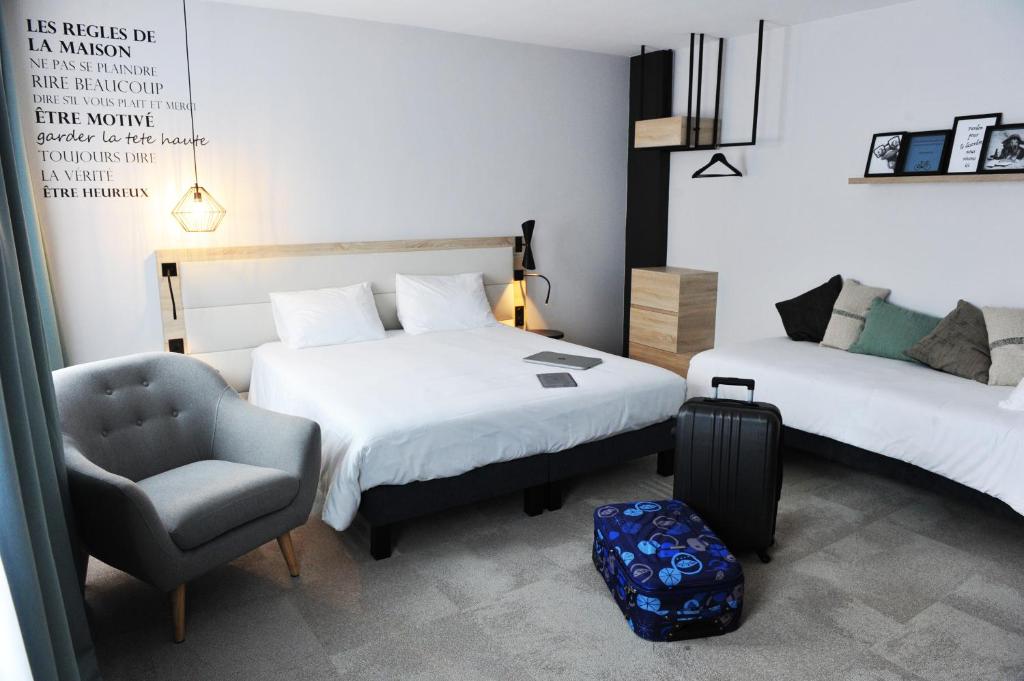 a bedroom with two beds and a chair and a suitcase at Urban Style Hotel de France in Vannes