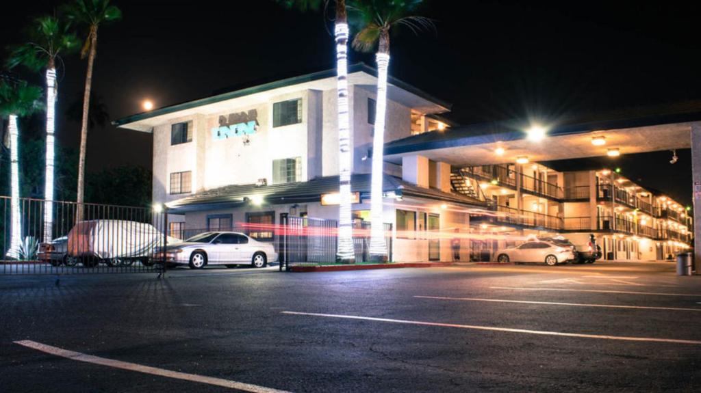 un edificio con coches estacionados en un estacionamiento por la noche en Morada Inn en Anaheim