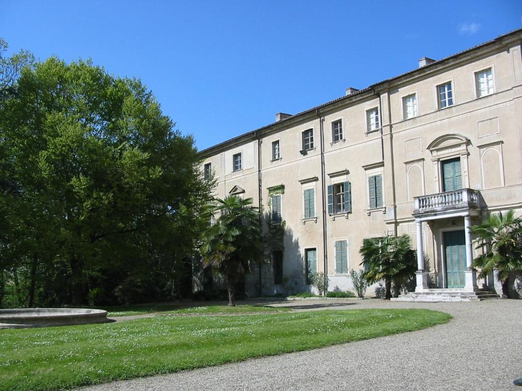 un gran edificio blanco con árboles delante de él en Agriturismo Villa Gropella, en Valenza