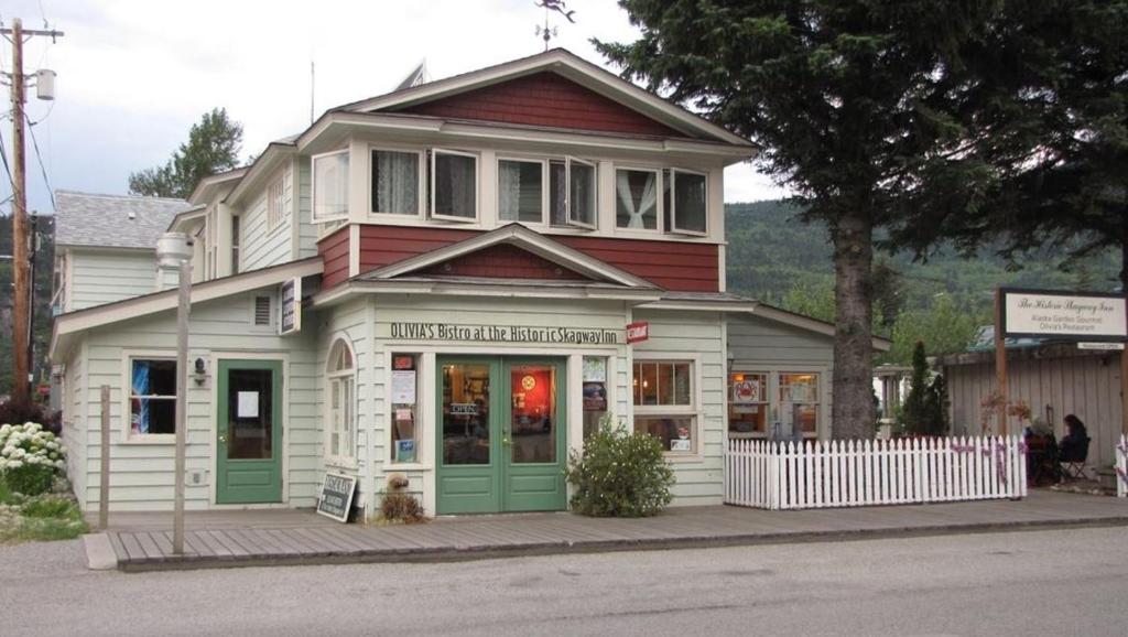 a white and red house with green doors on a street at Historic Skagway Inn in Skagway