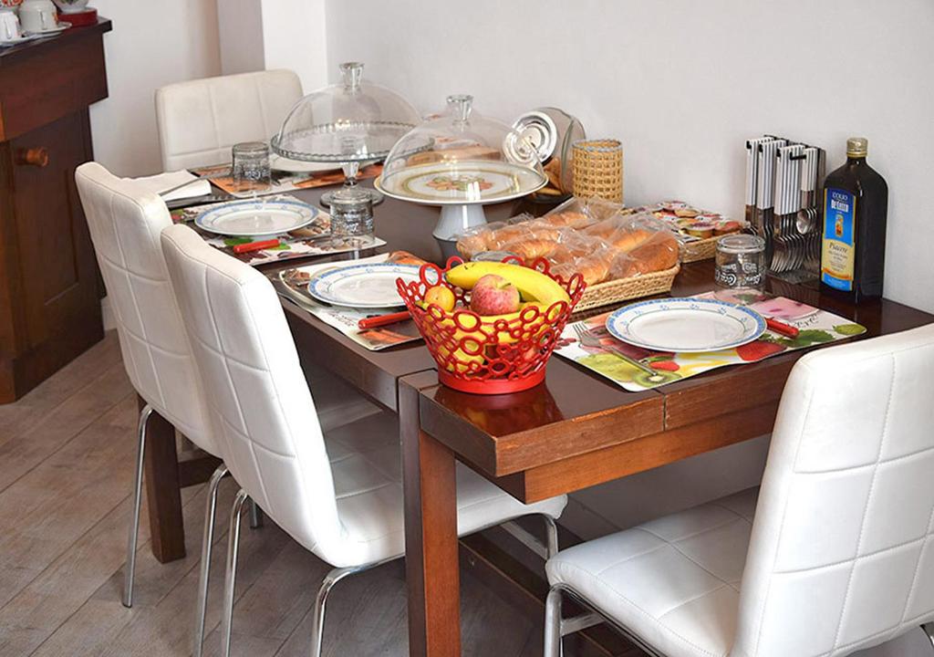 mesa de comedor con sillas blancas y mesa con comida en B&B Borfuro en Bergamo