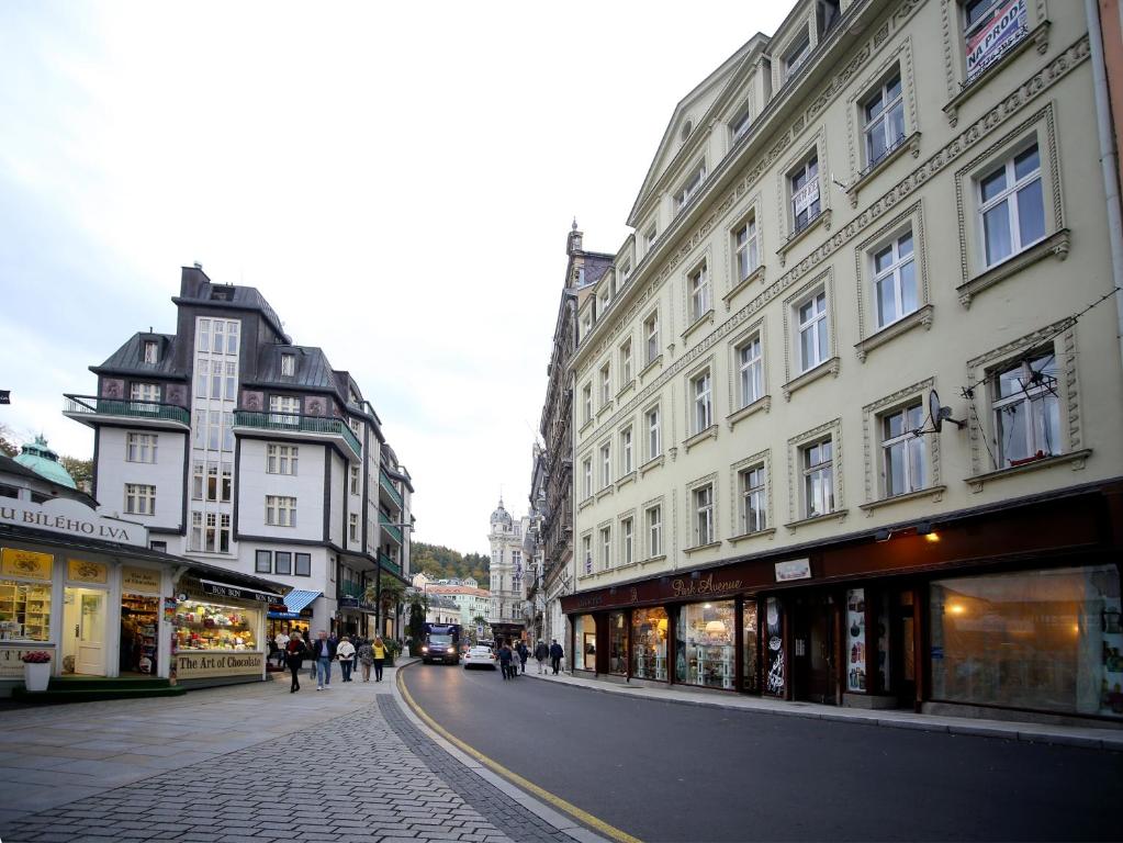 una calle de la ciudad con edificios y gente caminando por la calle en Apartmán u Vřídla, ul. Tržiště. en Karlovy Vary