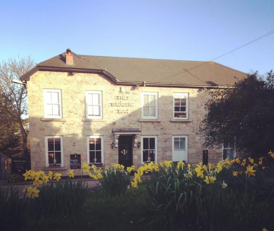 een oud bakstenen gebouw met bloemen ervoor bij The Badger Inn in Carbis Bay