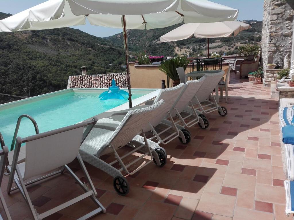 una piscina con sillas y una sombrilla en el patio en B&B Il Belvedere en Guardialfiera