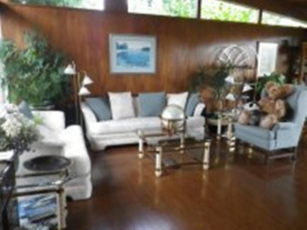 a living room with white couches and a wooden wall at Beach Estates Inn Bed and Breakfast in Nanaimo