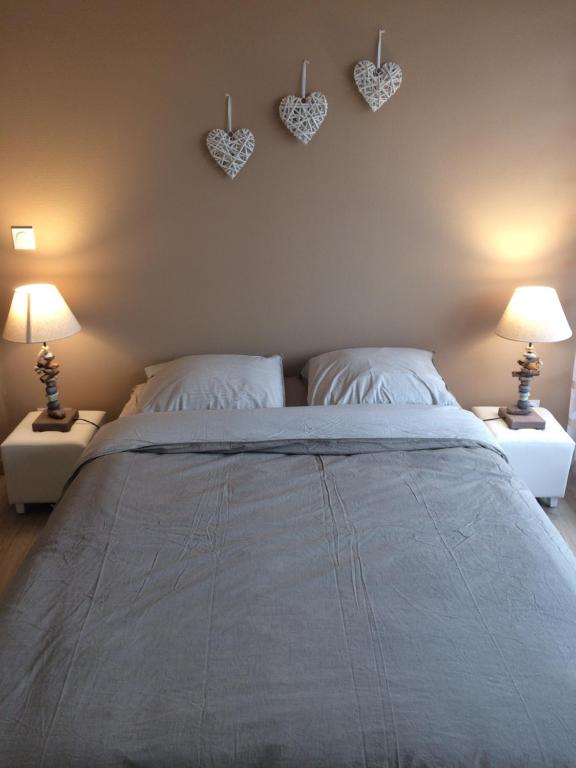 - une chambre avec un grand lit et des cœurs au mur dans l'établissement Meublé de Tourisme Au Troubadour, vaste T2 proximité République avec garage, à Dijon