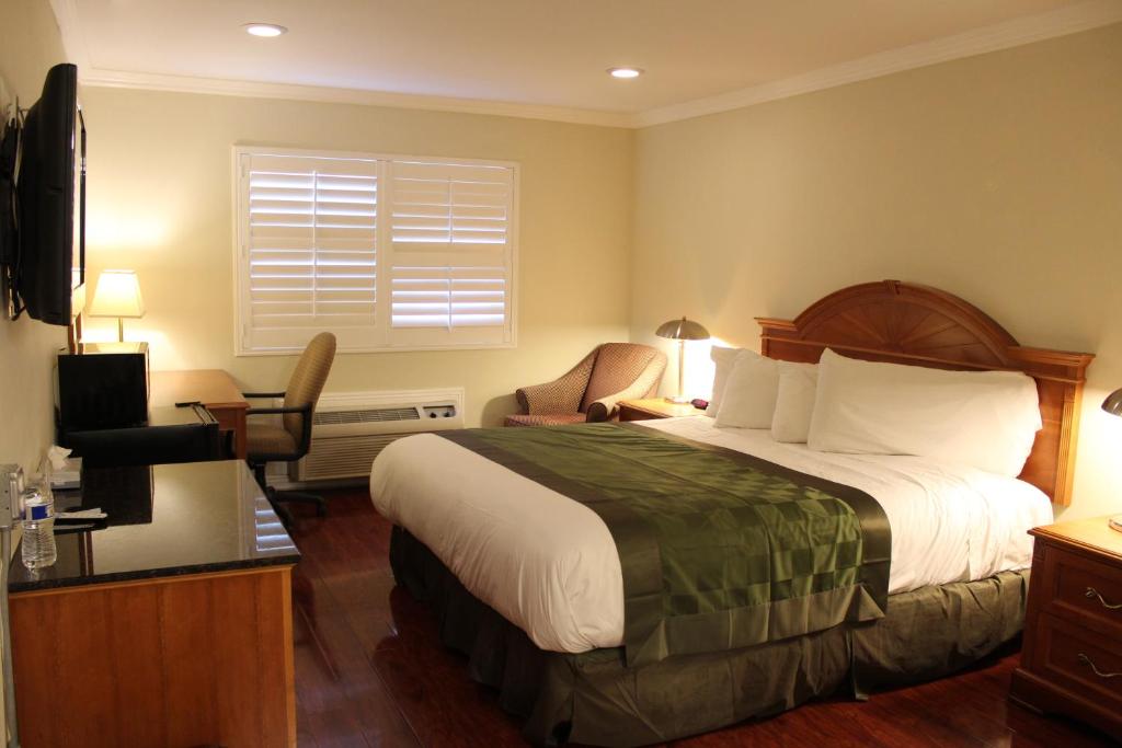 Habitación de hotel con cama y silla en Garden Inn San Gabriel, en San Gabriel