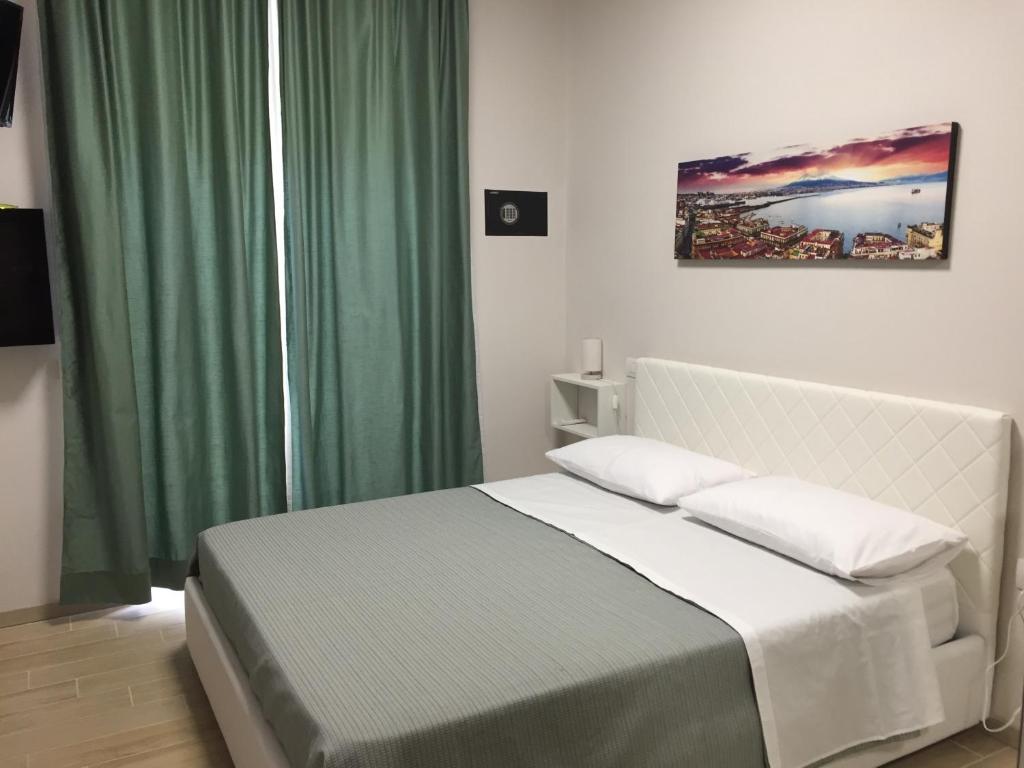 a bedroom with a white bed with a green curtain at Villa Augustea in Somma Vesuviana