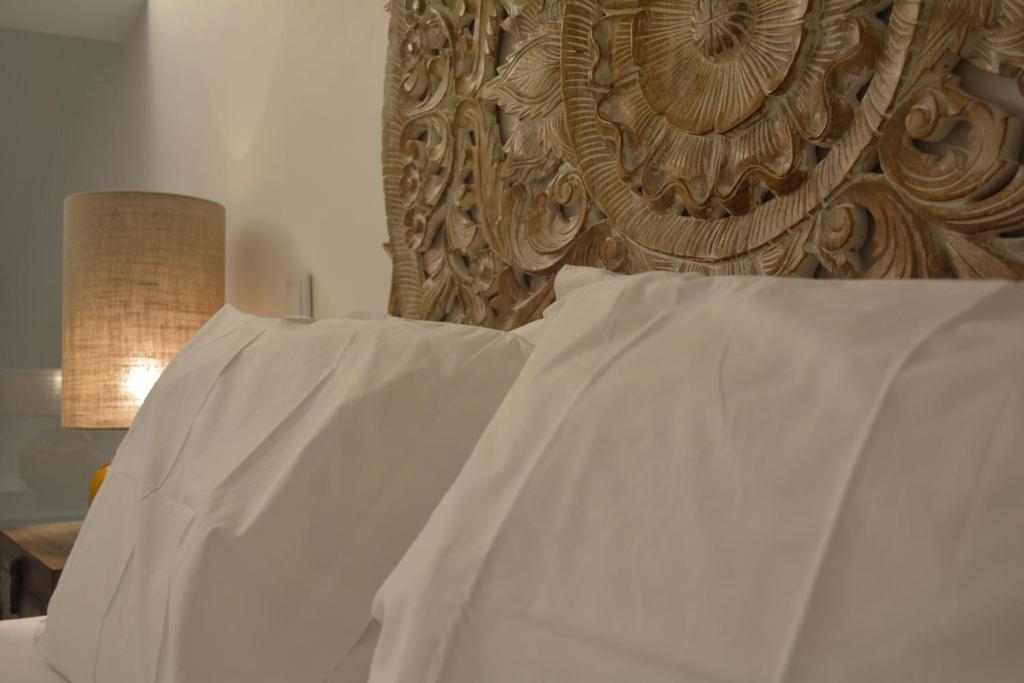 a bed with white sheets and a wooden headboard at 10 Boutique House in Alcochete