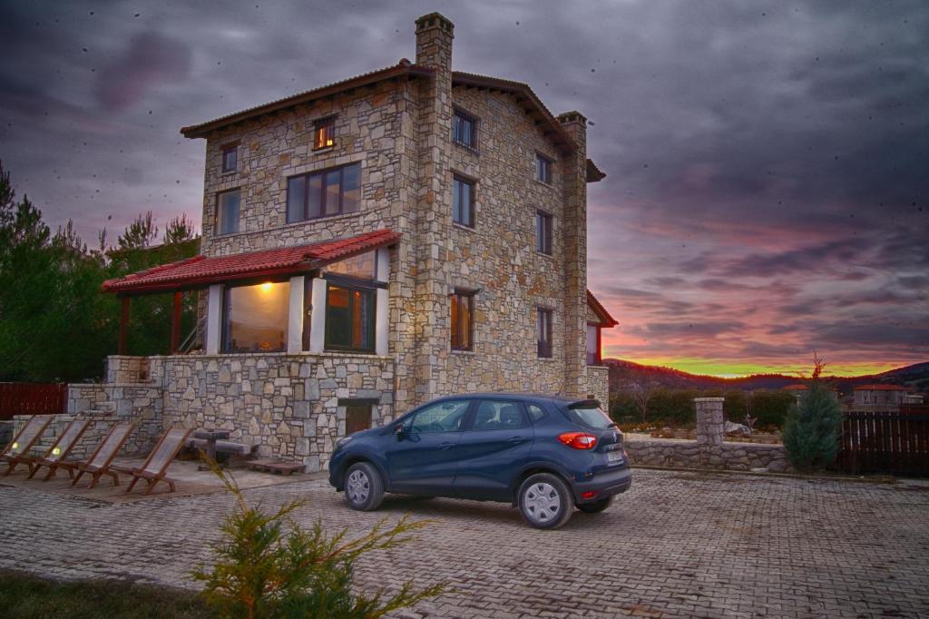 a blue car parked in front of a stone house at Parnassos Ski Chalet in Arachova