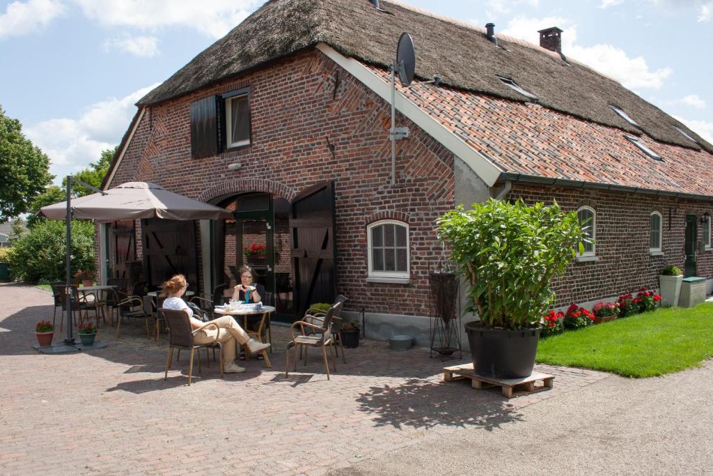 a woman sitting at a table outside of a building at De Martiene Plats B&B & Appartement in Merselo