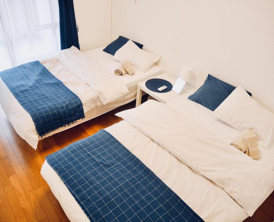 um quarto com duas camas e um colchão azul em Izumi Apartment em Osaka