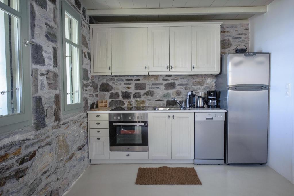 a kitchen with white appliances and a stone wall at Serifos Dream Houses near the sea in Ganema