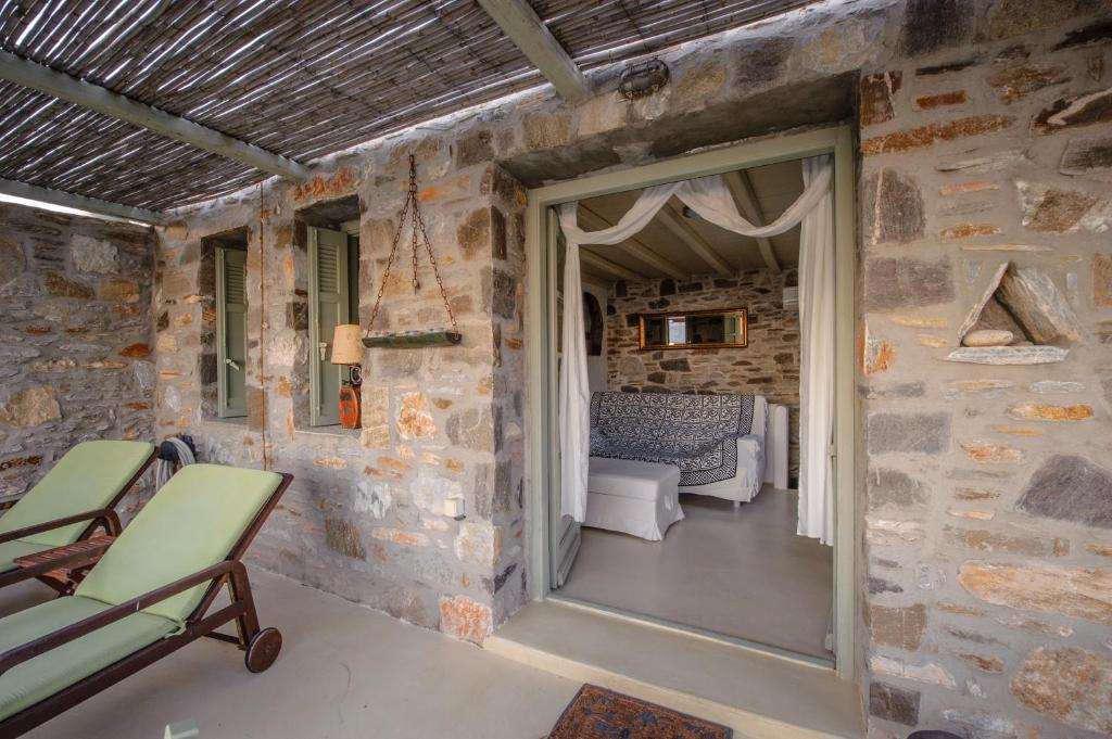 a room with a stone wall and a door with a chair at Serifos Dream Houses near the sea in Ganema