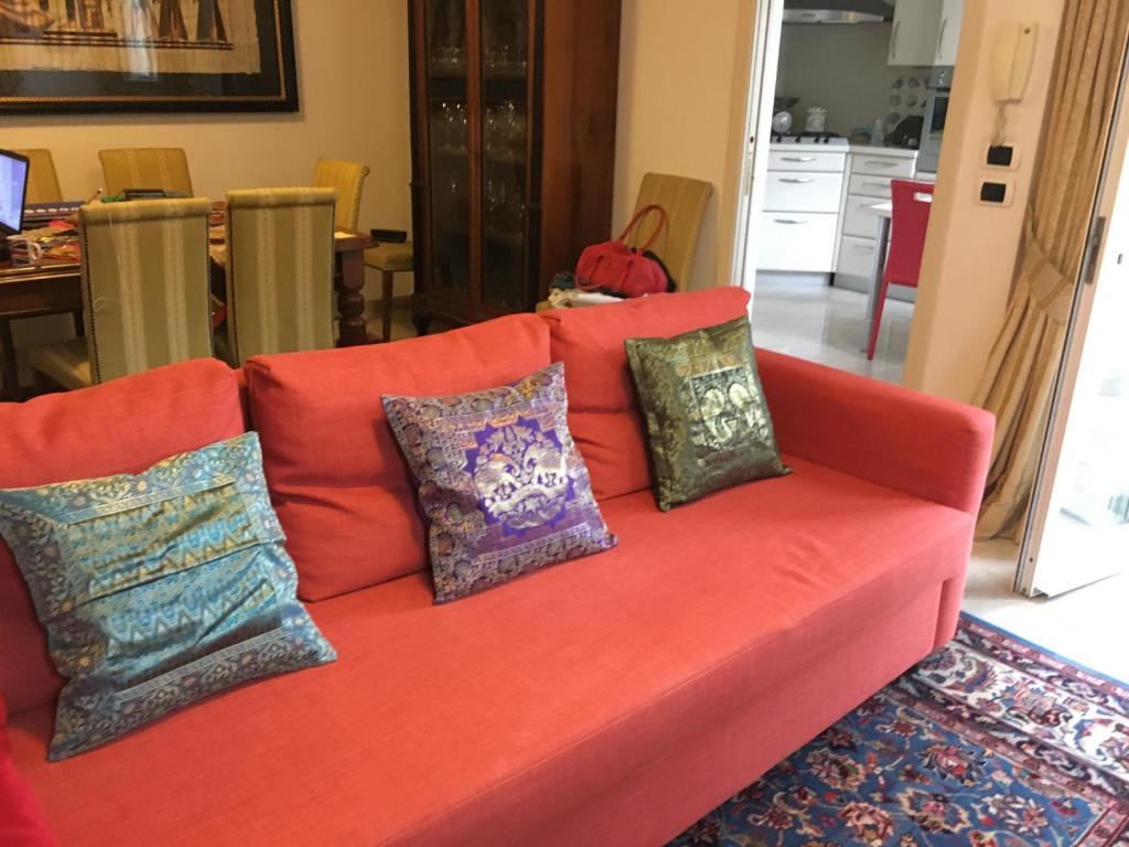 a orange couch with pillows on it in a living room at Apartment Whenlifeisbetter in Casal Palocco