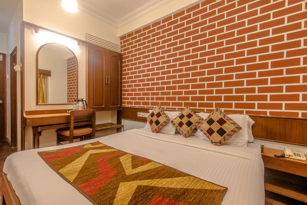 ムンバイにあるHotel Mogul Palace - Near CST Stationのレンガの壁とベッドが備わるベッドルーム1室が備わります。