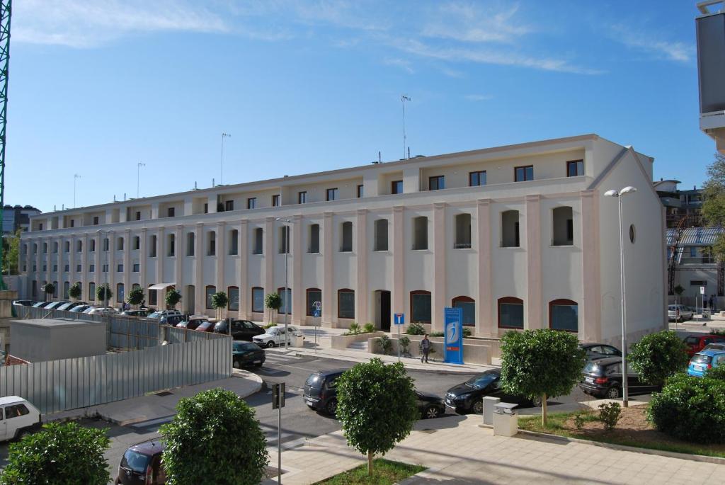 un gran edificio blanco con coches aparcados en un aparcamiento en Residence Trani en Trani