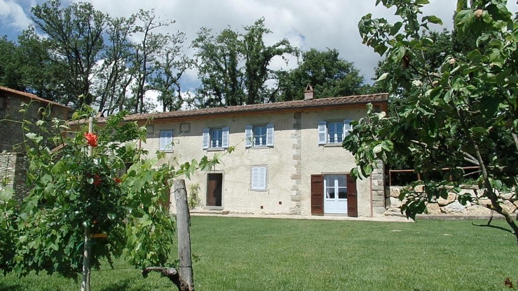 una vieja casa de piedra con un árbol delante en La Breccia di Anghiari, en Anghiari